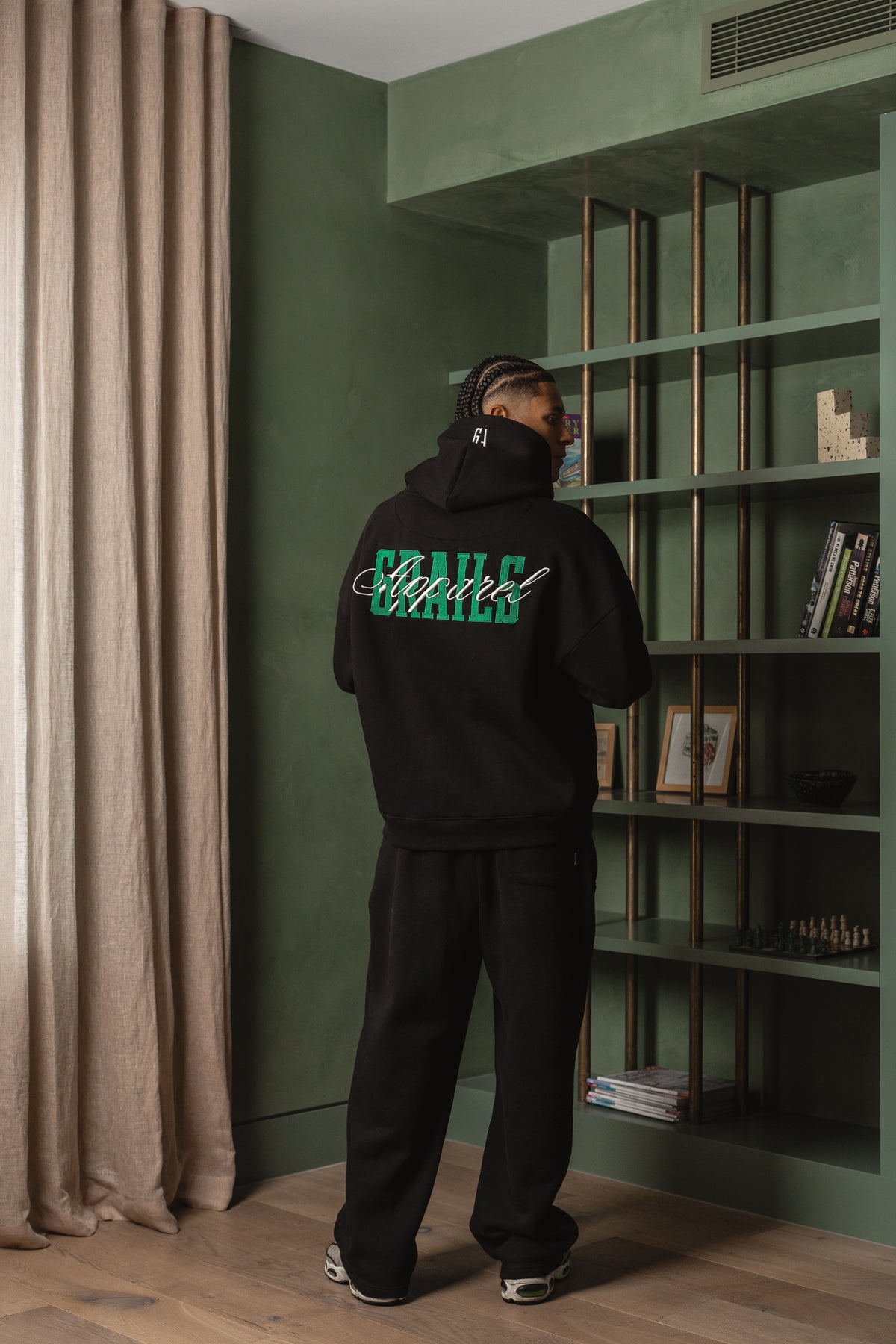 Varsity Hoodie in black worn back-on, green tatami GRAILS back embroidery with raised white Apparel script - Grails Apparel 460gsm hoodie